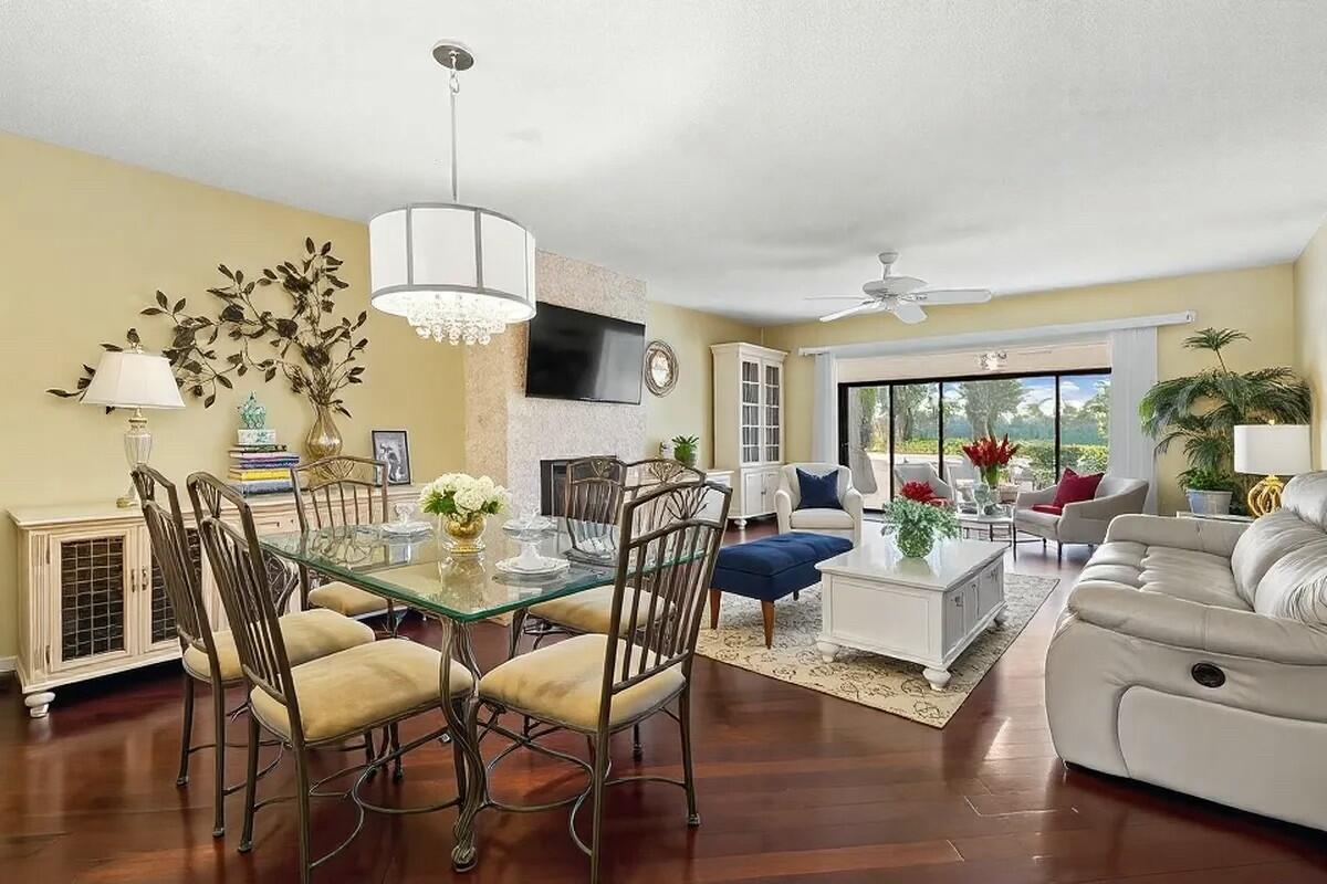 An open-concept living and dining room with hardwood floors, a fireplace, and glass sliding doors — 603 Laconia Circle, Lake Worth FL 33467, LAKE WORTH, FL