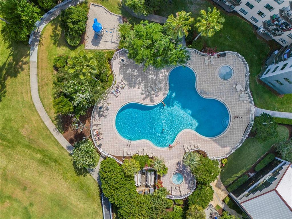 An aerial view shows a swimming pool with a hot tub and a playground nearby — 6165 CARRIER DRIVE UNIT 3207, ORLANDO, FL