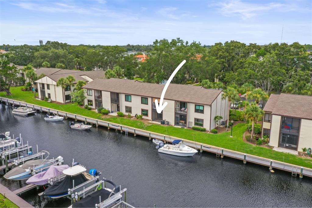 An aerial view shows a multi-story waterfront condominium building with a boat docked outside — 358 MOORINGS COVE DRIVE UNIT 4B, TARPON SPRINGS, FL