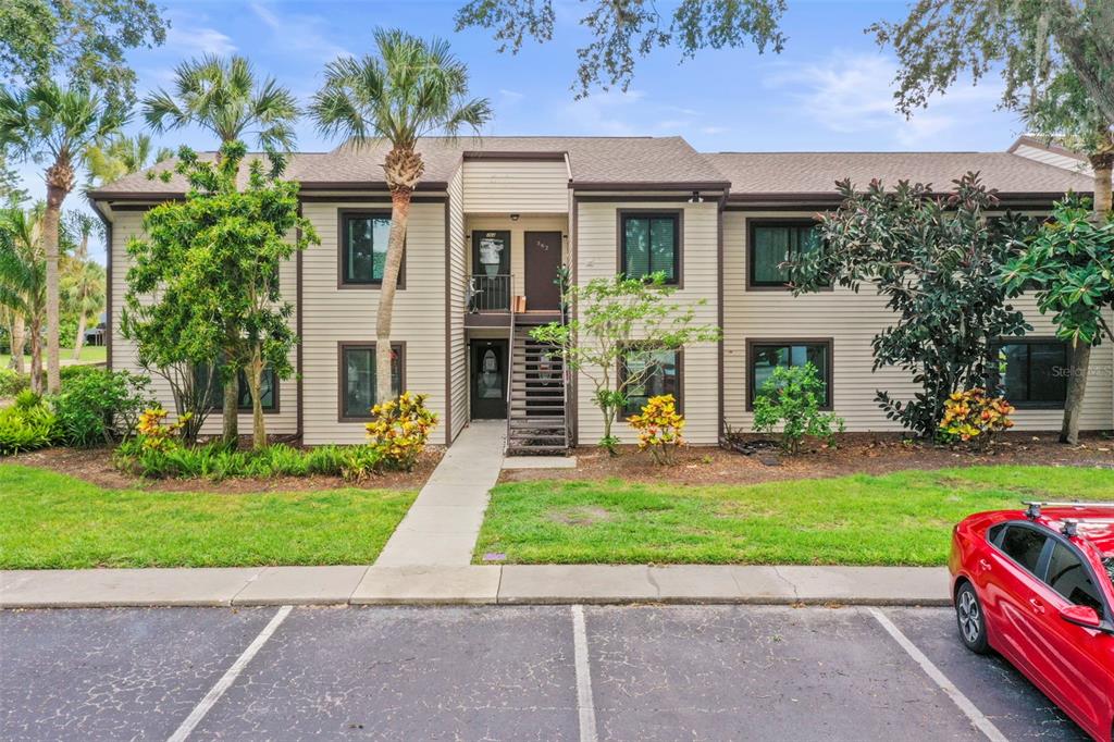 A two-story apartment building with beige siding, a central staircase, and a parking lot — 358 MOORINGS COVE DRIVE UNIT 4B, TARPON SPRINGS, FL