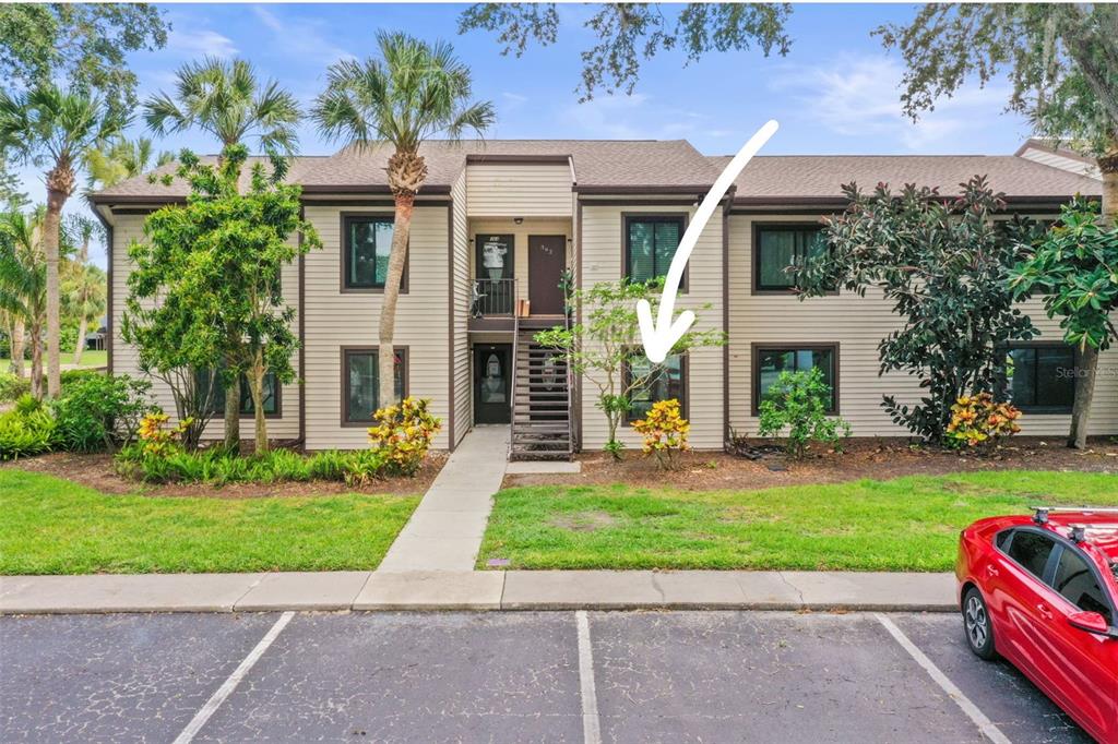 Exterior view of a two-story apartment building with beige siding and a central staircase — 358 MOORINGS COVE DRIVE UNIT 4B, TARPON SPRINGS, FL