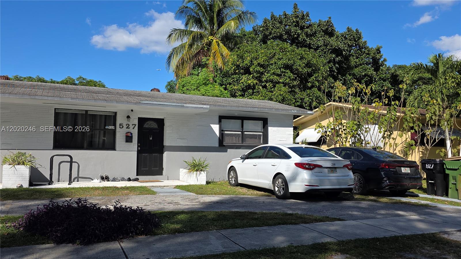 A single-story house with white and gray exterior walls features a front door and two cars — 525 NE 132nd Ter # 527, North Miami FL 33161, NORTH MIAMI, FL