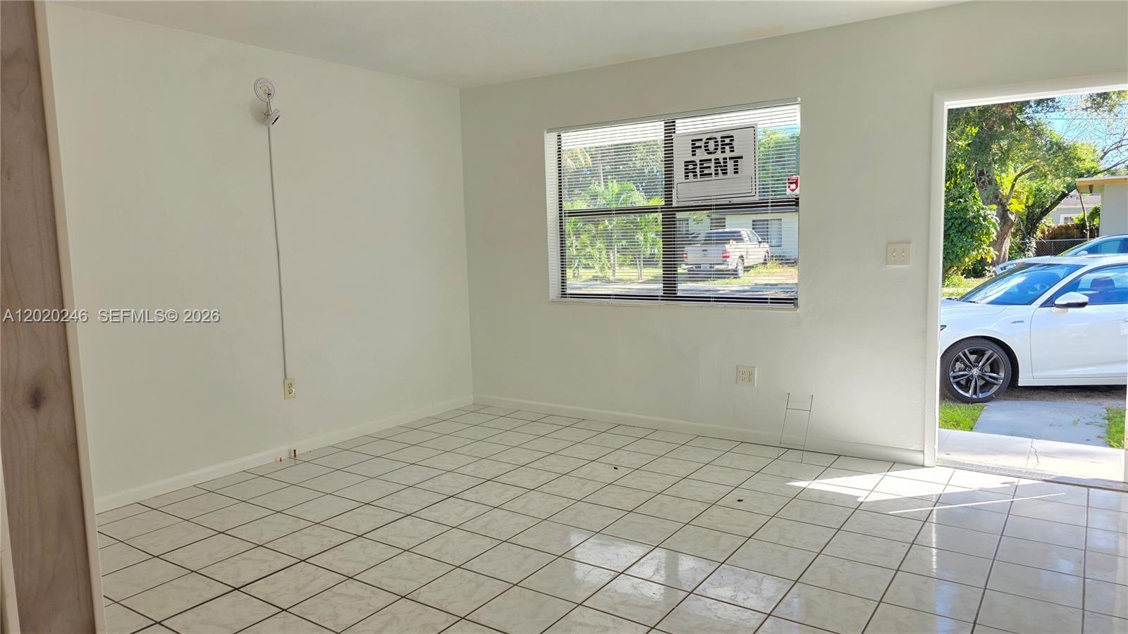 An empty room features white tile flooring, white walls, a window, and an open doorway — 525 NE 132nd Ter # 527, North Miami FL 33161, NORTH MIAMI, FL