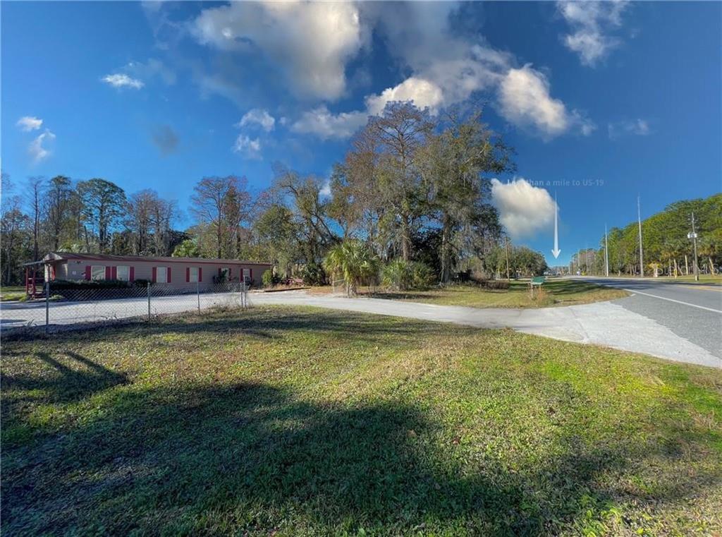 A grassy lot with a mobile home and a driveway next to a paved road — 8144 W GROVER CLEVELAND BOULEVARD, HOMOSASSA, FL