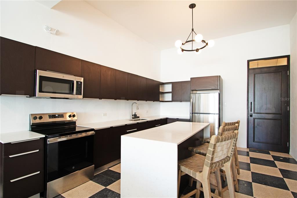A modern kitchen features dark cabinetry, white countertops, a central island, and a checkered floor — 254-256 SAN FRANCISCO STREET UNIT 203, SAN JUAN, PR