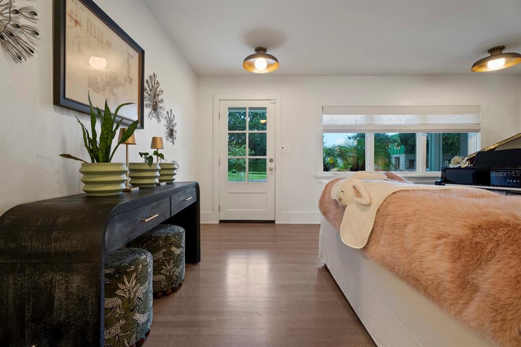 A room with wood floors, a console table, two stools, and a piano near a window — 890 N PHELPS AVENUE, WINTER PARK, FL