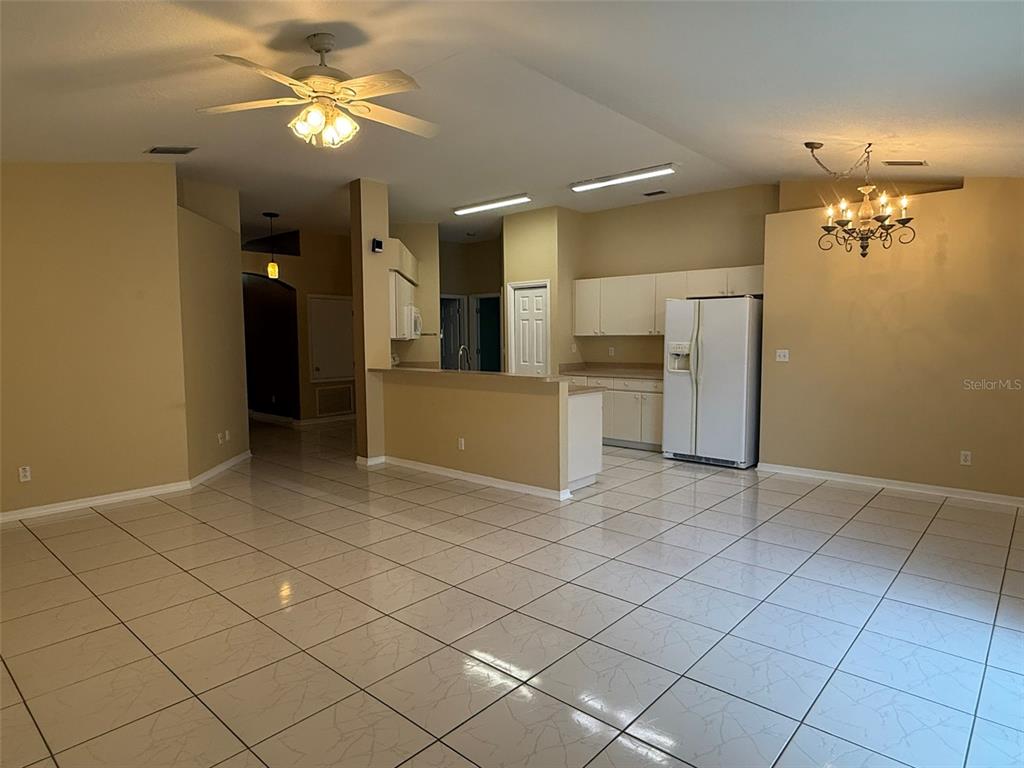 An open-concept kitchen and living area features white cabinets, tile flooring, and a ceiling fan — 4707 RAMSHEAD DRIVE, VALRICO, FL