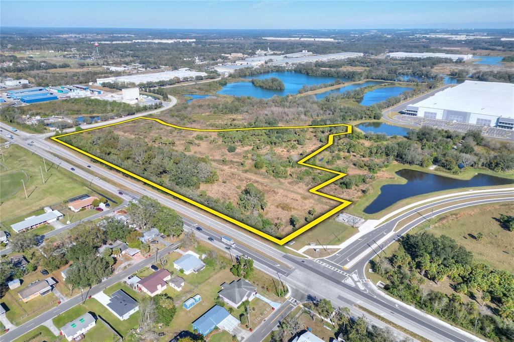 An aerial view shows a vacant, irregularly shaped lot outlined in yellow near a highway — 674 PARK ROAD, PLANT CITY, FL
