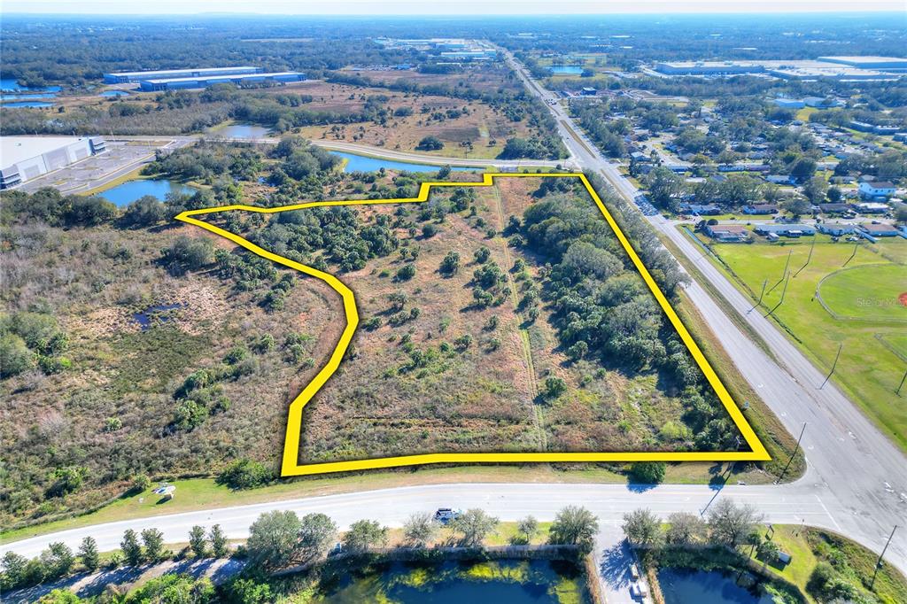 An aerial view shows a vacant, irregularly shaped plot of land outlined in yellow — 674 PARK ROAD, PLANT CITY, FL