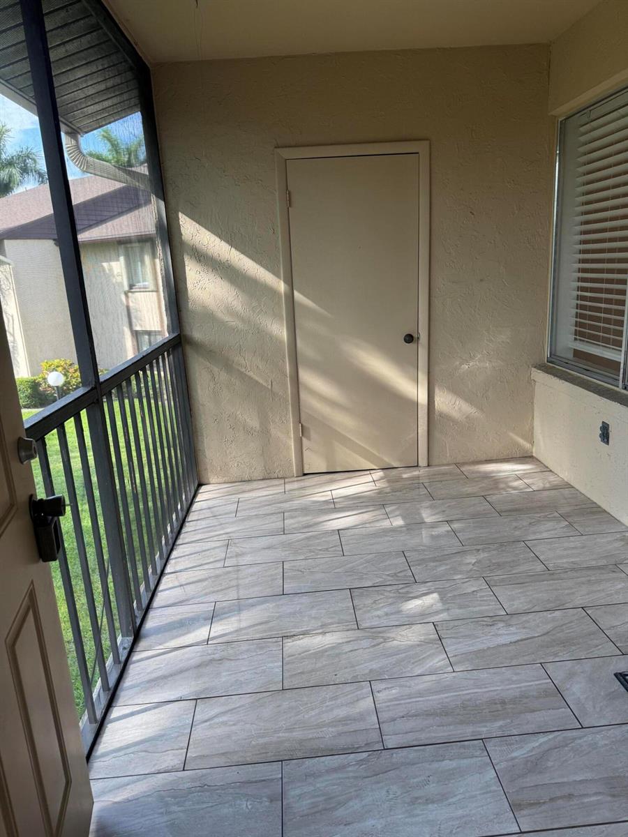 A screened-in porch with light-colored wood-look tile flooring and a storage closet door — 435 Pine Glen Lane # 2, FL 33463, FL