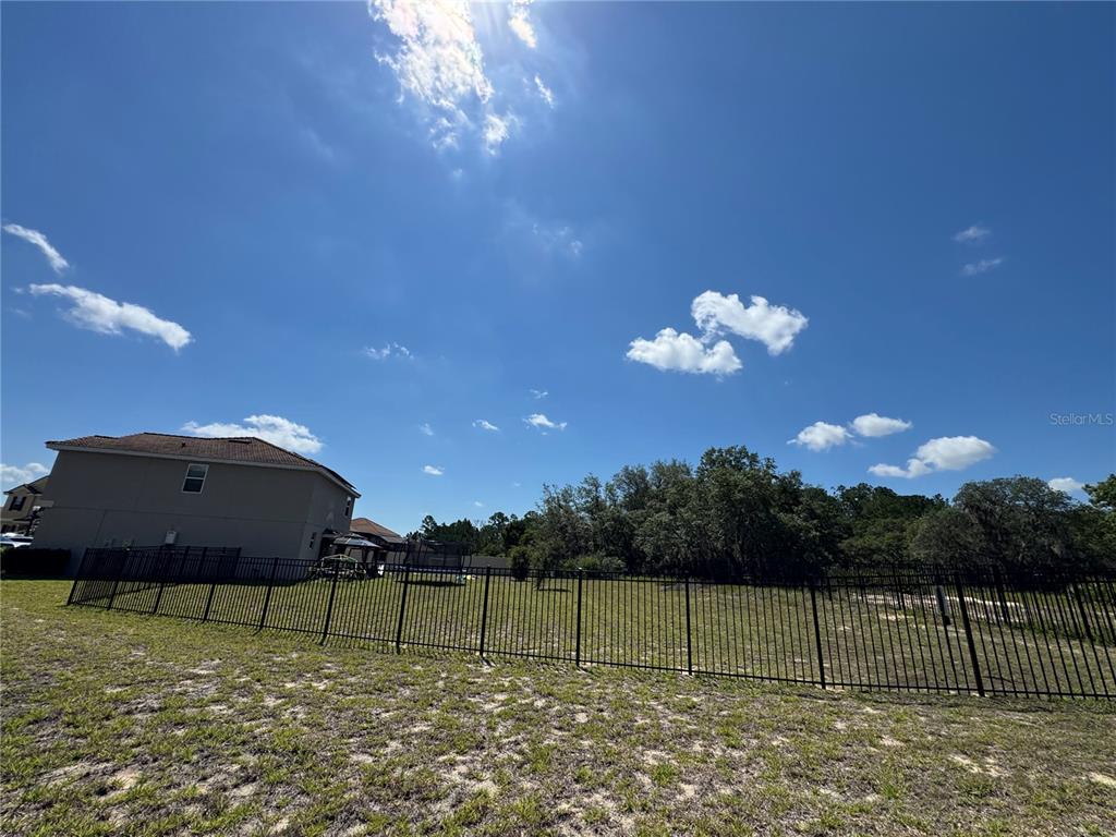 A black metal fence encloses a grassy backyard behind a two-story house — 1512 OAK MARSH LOOP, DAVENPORT, FL