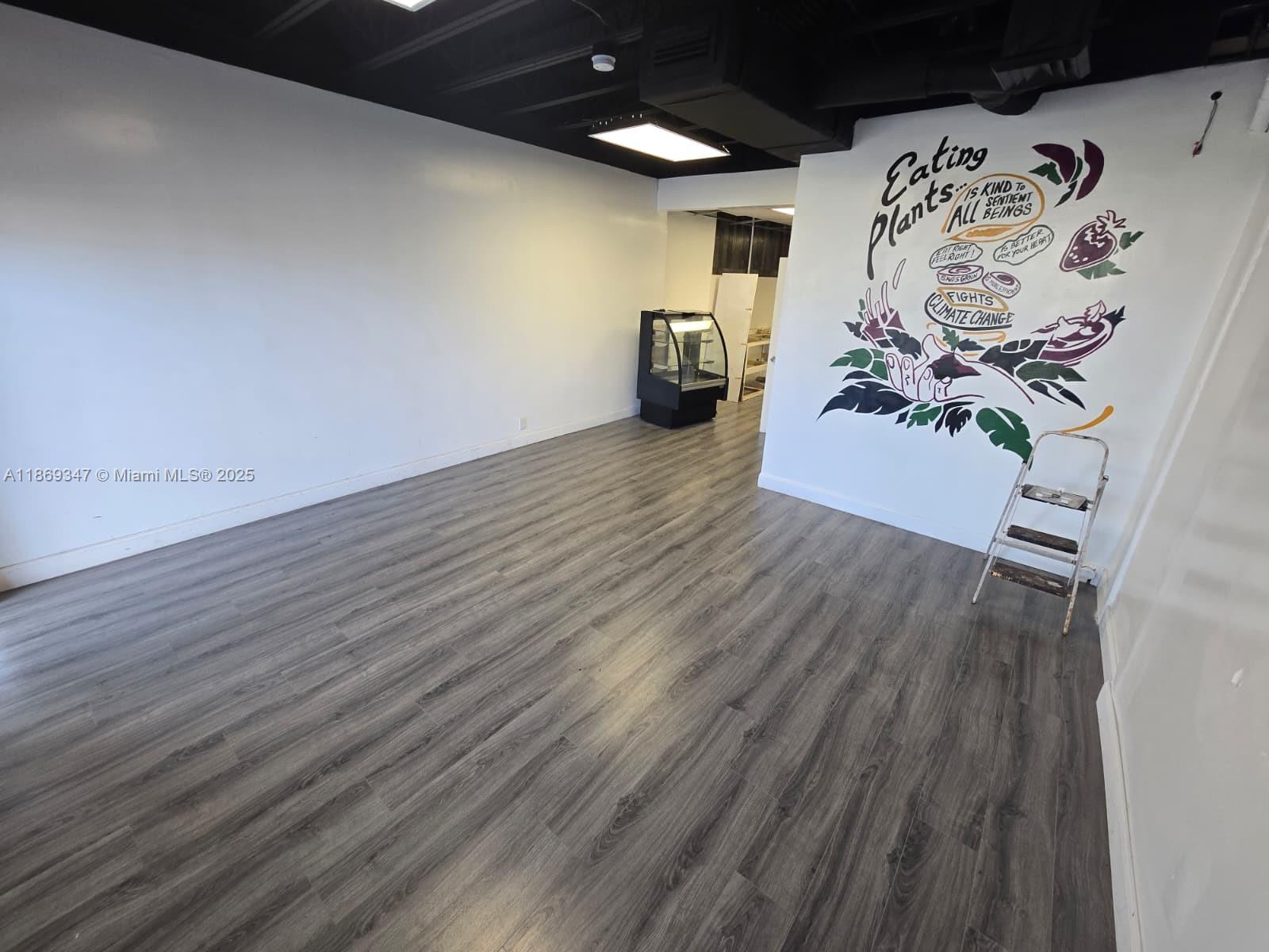 An empty commercial space features gray wood-look flooring, a black ceiling, and a mural wall — 2501 N State Road 7 # 2503, Margate FL 33063, MARGATE, FL