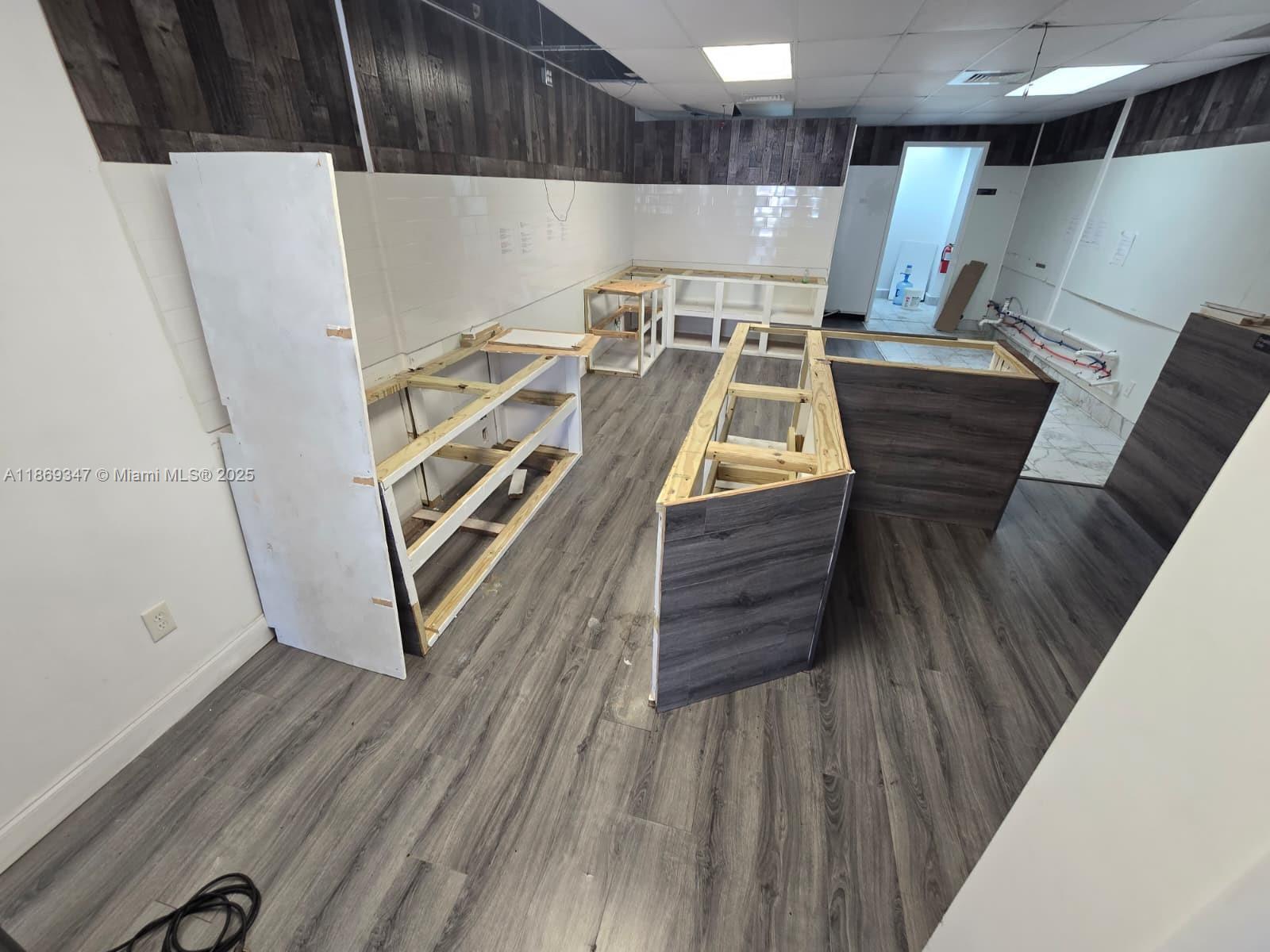 This commercial space features unfinished wooden cabinetry, gray wood-look flooring, and dark wood-paneled walls — 2501 N State Road 7 # 2503, Margate FL 33063, MARGATE, FL
