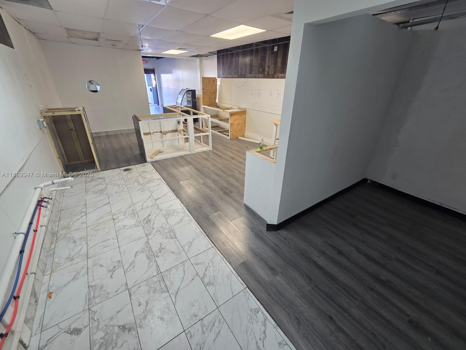 An unfinished commercial space features a mix of marble-look tile and grey wood-look flooring — 2501 N State Road 7 # 2503, Margate FL 33063, MARGATE, FL