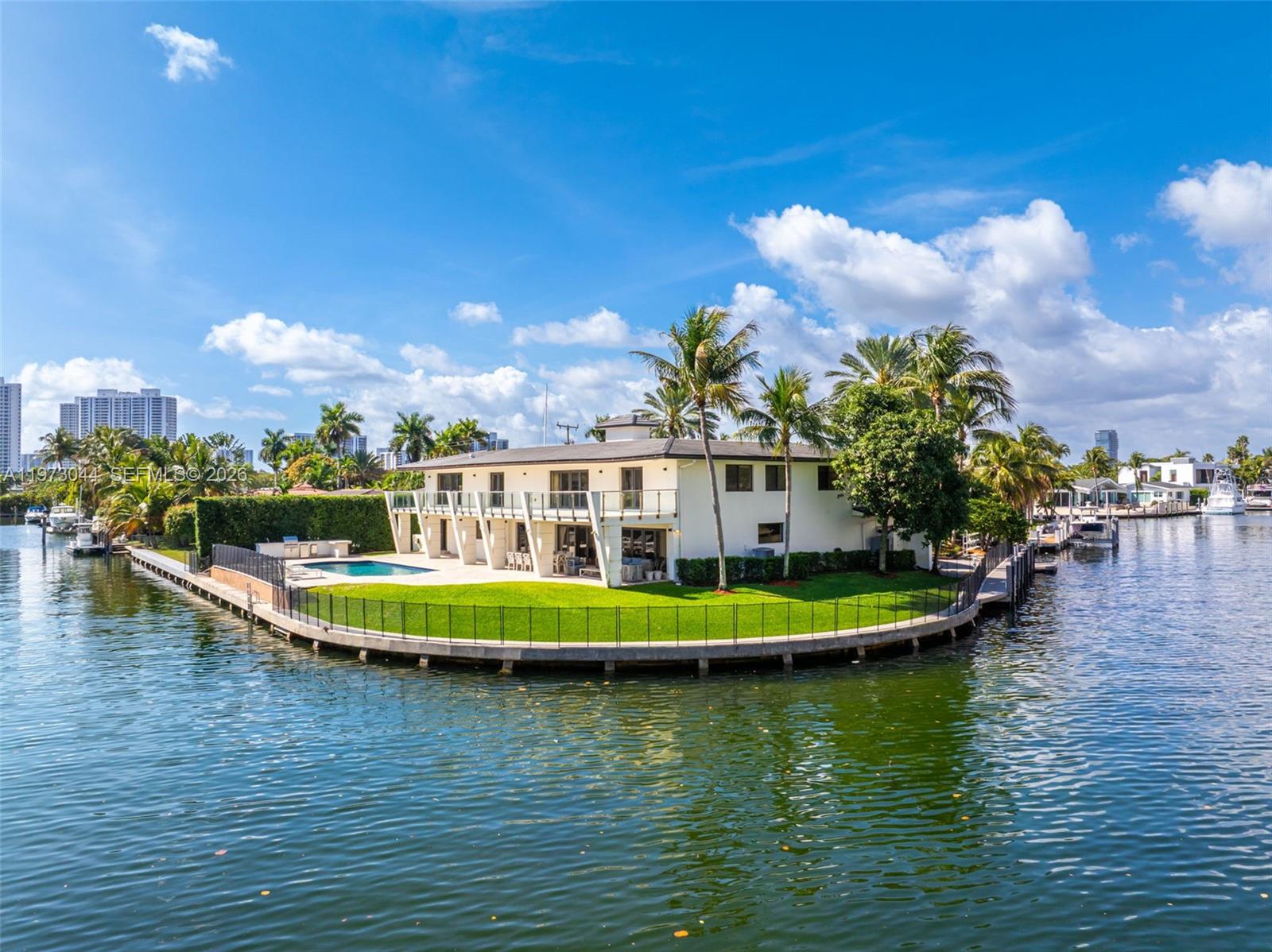 A two-story white house with a pool sits on a waterfront point with palm trees — 501 Hibiscus Dr, Hallandale Beach FL 33009, HALLANDALE BEACH, FL