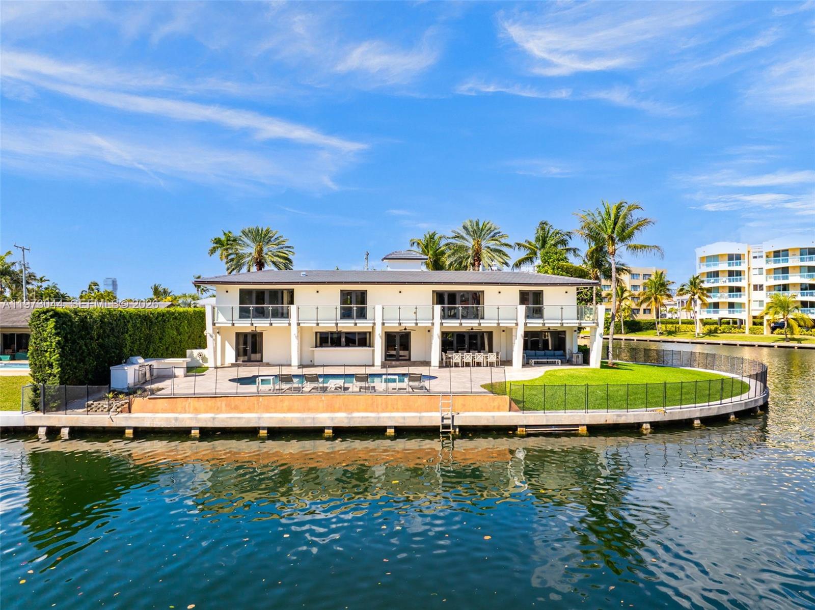 A two-story waterfront house features a swimming pool, patio, and glass balcony railings — 501 Hibiscus Dr, Hallandale Beach FL 33009, HALLANDALE BEACH, FL