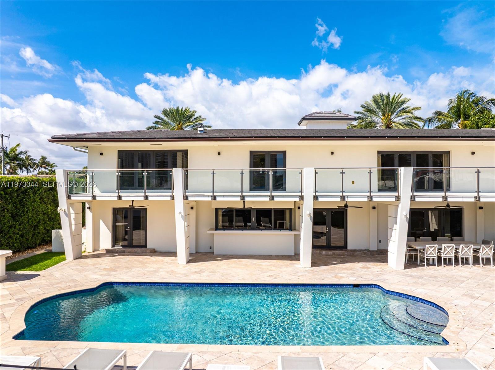 A two-story house with a balcony, patio, and swimming pool under a blue sky — 501 Hibiscus Dr, Hallandale Beach FL 33009, HALLANDALE BEACH, FL