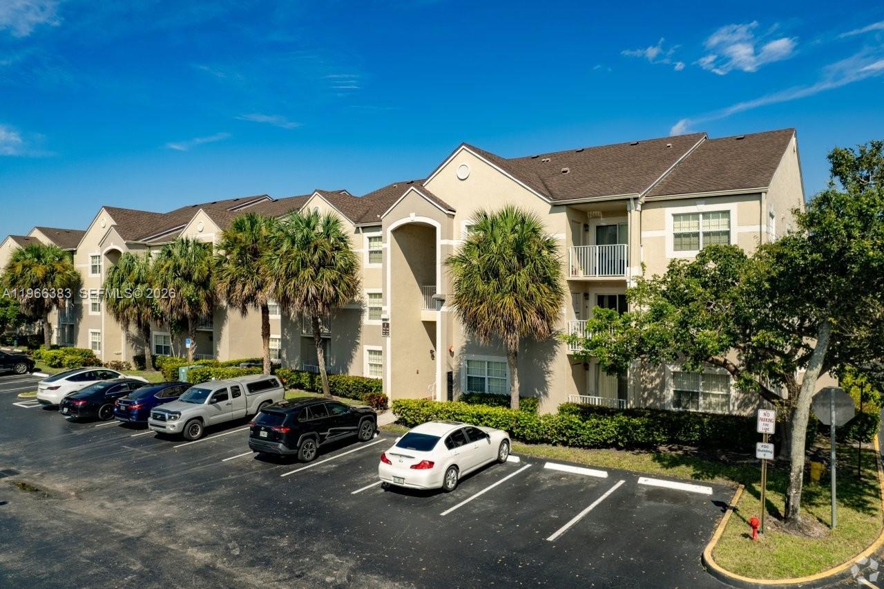 An exterior view of a multi-story apartment building with a parking lot in front — NORTH LAUDERDALE, FL