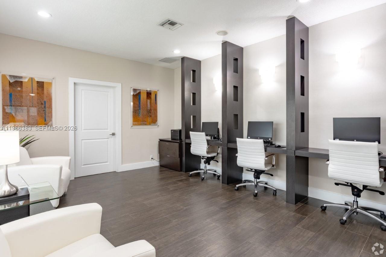 A business center features three computer workstations with white chairs and dark wood partitions — NORTH LAUDERDALE, FL