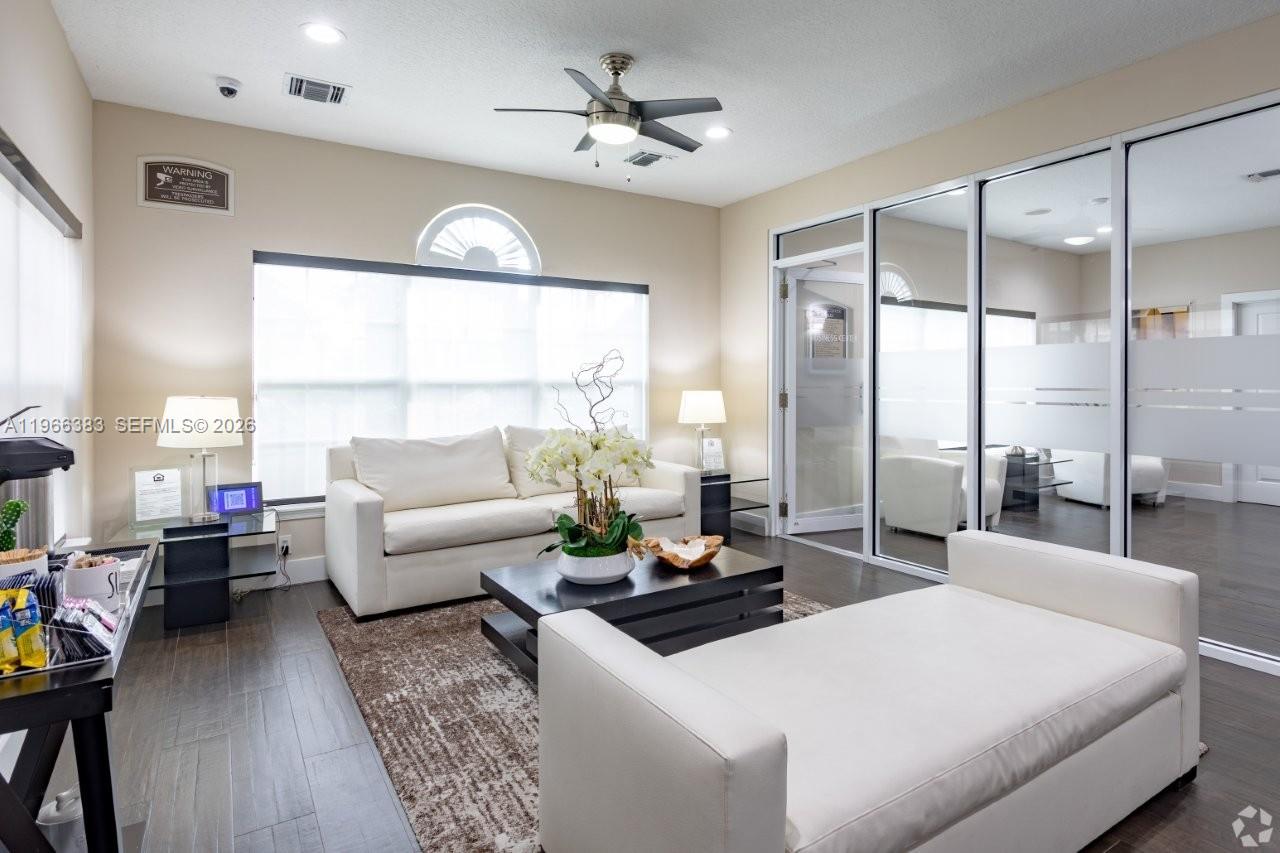 A waiting area features white sofas, a dark coffee table, and glass-walled office spaces — NORTH LAUDERDALE, FL