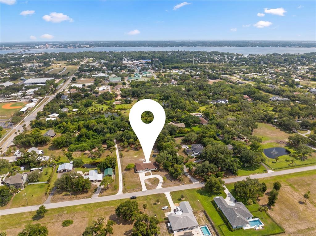 A white kitchen features a large quartz island, stainless steel appliances, and gold pendant lighting — 1515 21ST STREET W, PALMETTO, FL