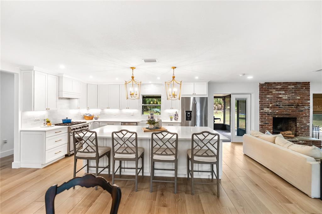 A bright kitchen features white cabinetry, a large central island with seating, and wood flooring — 1515 21ST STREET W, PALMETTO, FL
