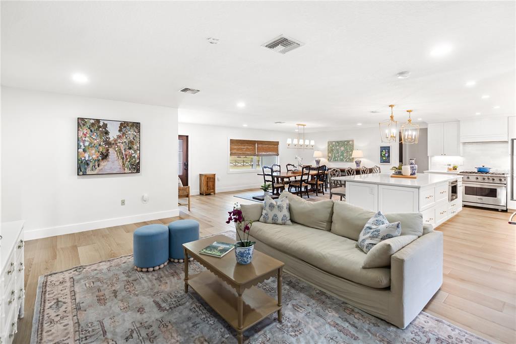 An open-concept living room, dining area, and kitchen feature light wood floors and white cabinetry — 1515 21ST STREET W, PALMETTO, FL
