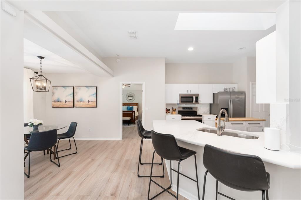 A modern kitchen with a white island, bar stools, and an adjacent dining area — 5248 NW 82ND COURT, OCALA, FL