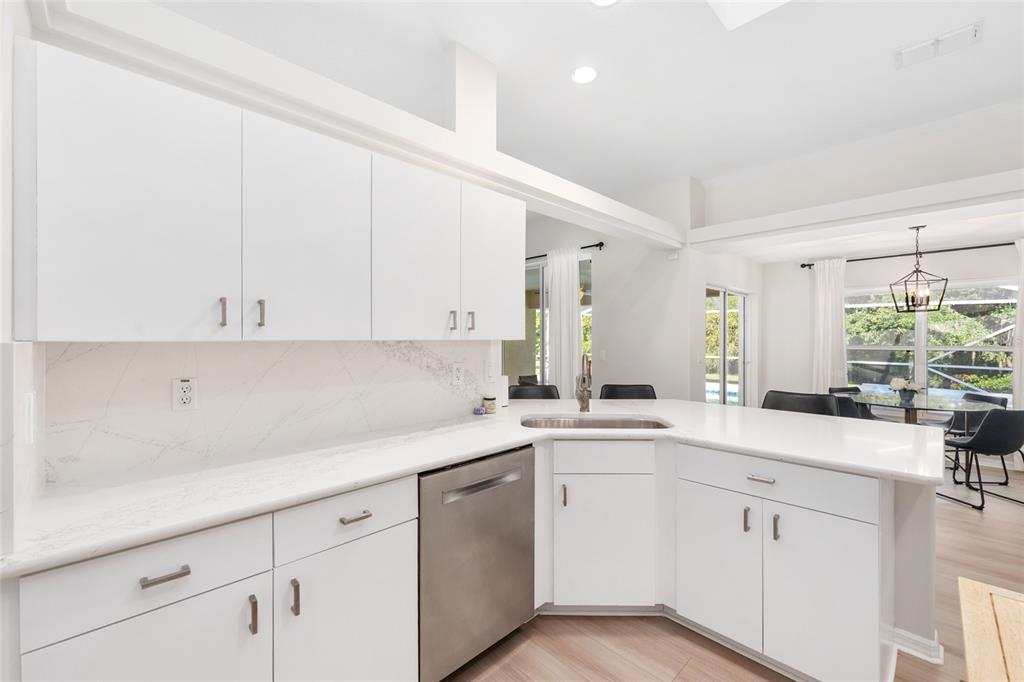 A modern kitchen features white cabinets, marble-style countertops, and stainless steel appliances — 5248 NW 82ND COURT, OCALA, FL
