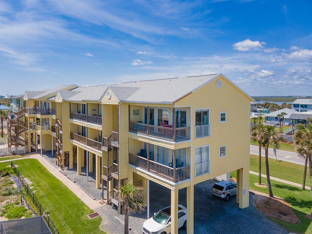 An elevated yellow multi-story apartment building with balconies and covered parking underneath — 6612 S ATLANTIC AVENUE UNIT 201, NEW SMYRNA BEACH, FL