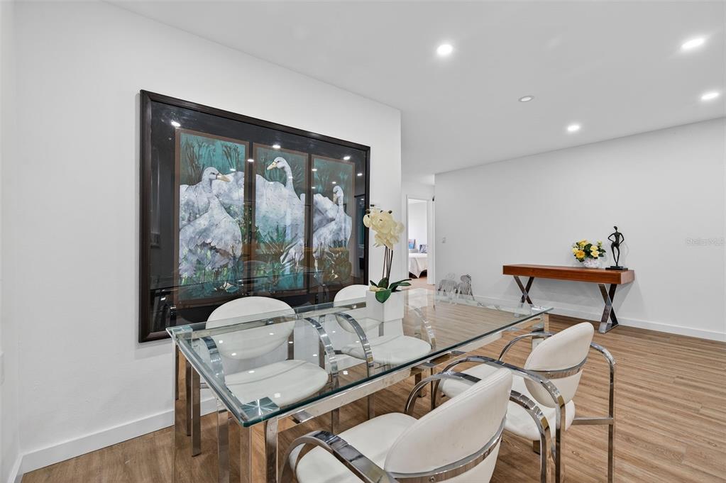 A dining room features a glass table, white chairs, and a large swan-themed wall art piece — 4916 TROON LANE, NEW PORT RICHEY, FL