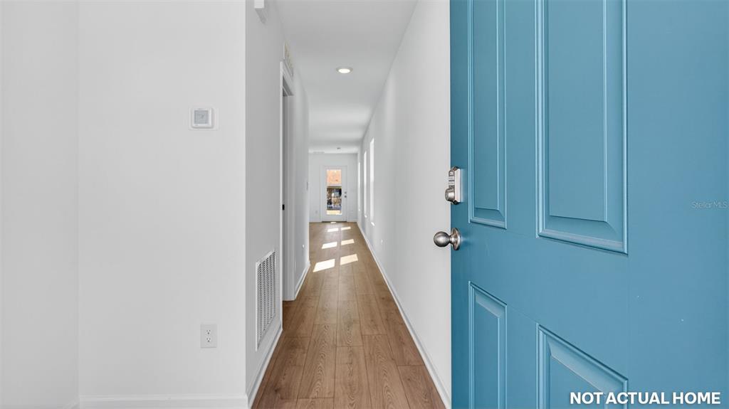 This is a rendering of a hallway with wood-look flooring and a blue front door — 21 FLAGSTICK LANE, BUNNELL, FL