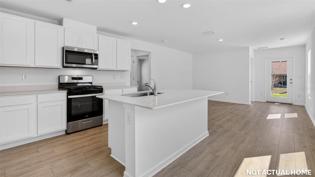 This rendering shows a kitchen with white cabinets, stainless steel appliances, and a center island — 21 FLAGSTICK LANE, BUNNELL, FL