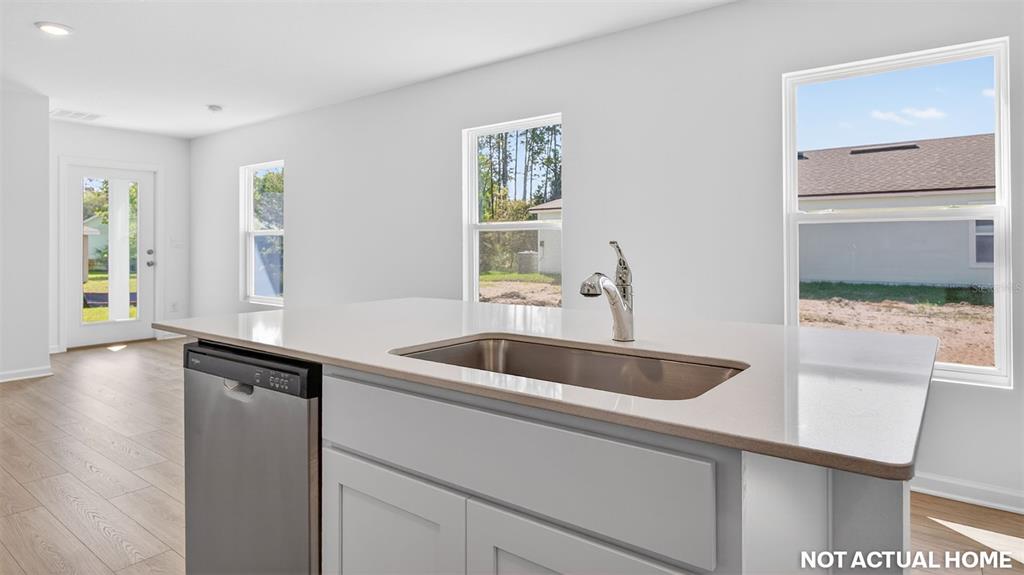 This kitchen island features a stainless steel sink and dishwasher against a white interior — 21 FLAGSTICK LANE, BUNNELL, FL