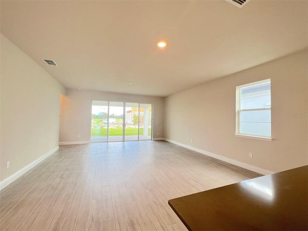 An open-concept living area features light-colored tile flooring, neutral walls, and large sliding glass doors — 4961 RAIN SHADOW DRIVE, ST CLOUD, FL