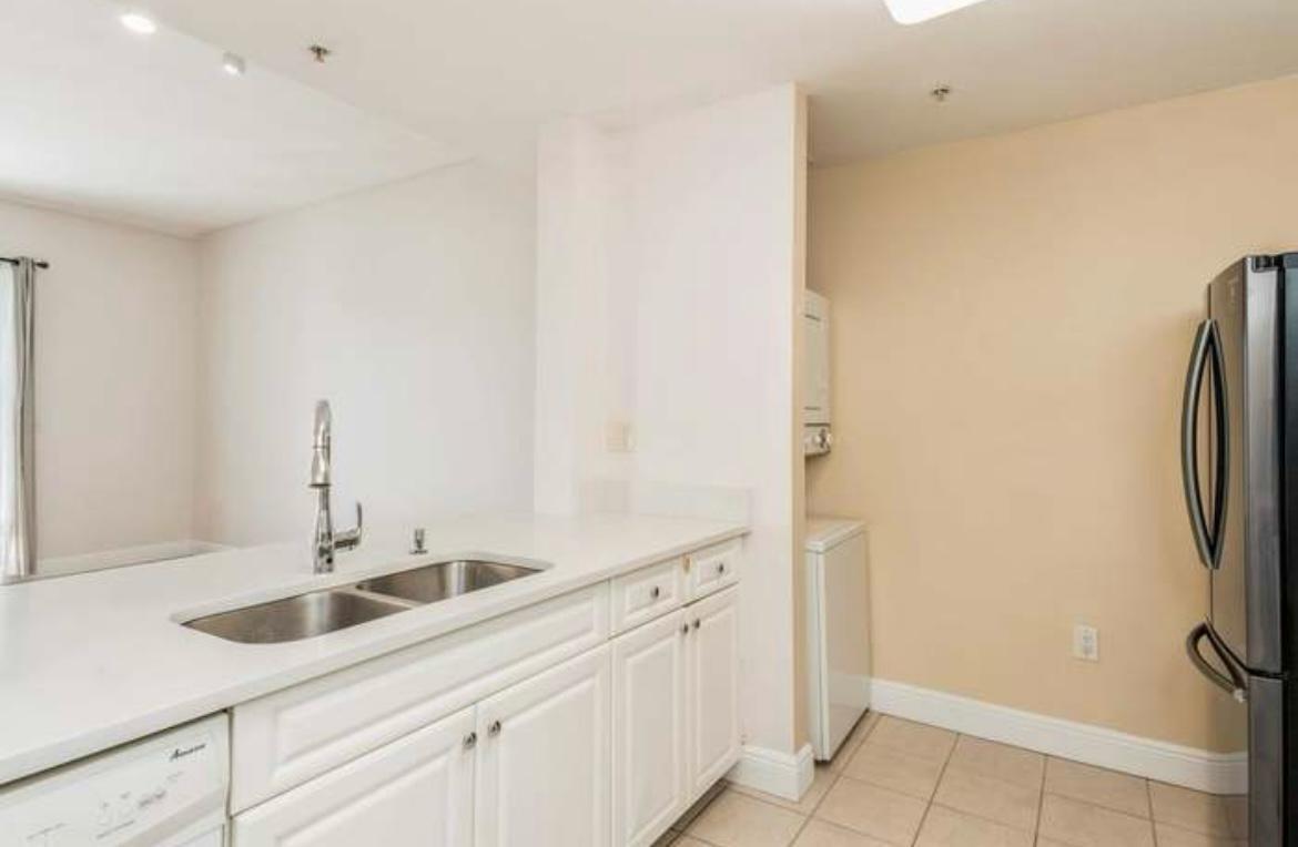 A kitchen with white cabinets, a double sink, and an adjacent laundry area — 1200 Town Center Drive # 305, Jupiter FL 33458, JUPITER, FL
