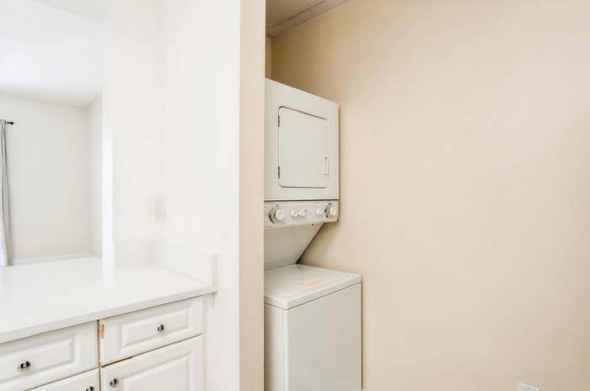 A stacked white washer and dryer unit is located in a small laundry alcove — 1200 Town Center Drive # 305, Jupiter FL 33458, JUPITER, FL