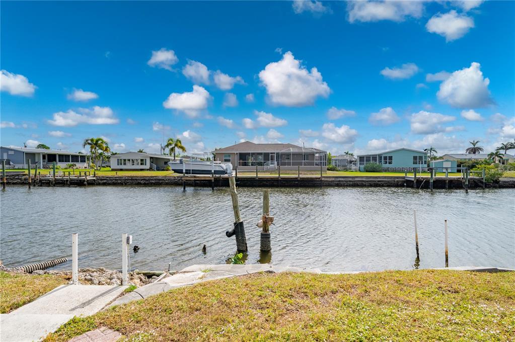 A canal view shows a house with a screened lanai and a private boat dock — 751 LONGBEACH COURT, PUNTA GORDA, FL
