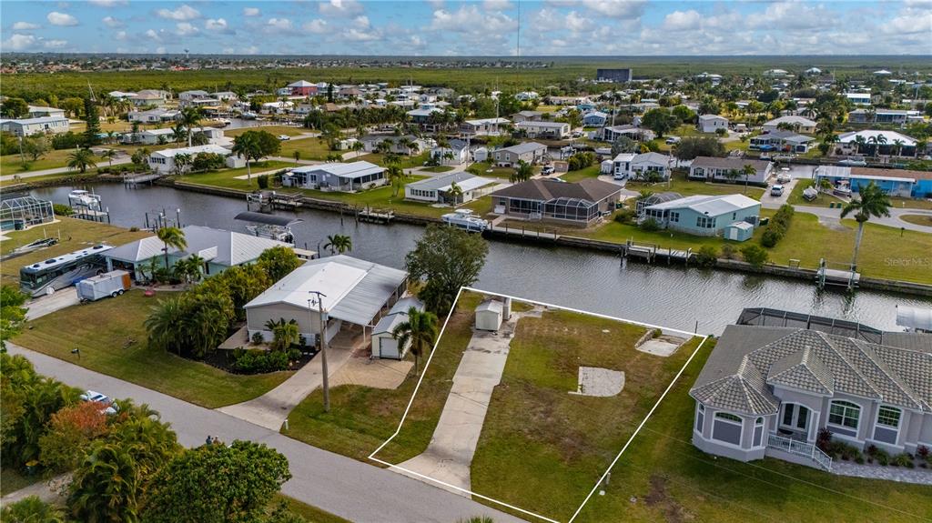 An aerial view shows a vacant waterfront lot with a concrete driveway and small shed — 751 LONGBEACH COURT, PUNTA GORDA, FL