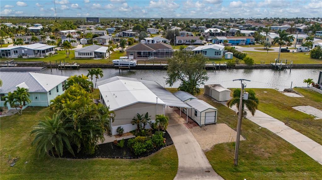 An aerial view shows a single-story house with a carport, shed, and canal-side backyard — 751 LONGBEACH COURT, PUNTA GORDA, FL