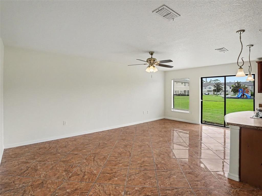 An empty room with brown tile flooring, a ceiling fan, and sliding glass doors — 6105 TIMBER CREST DRIVE, ST CLOUD, FL