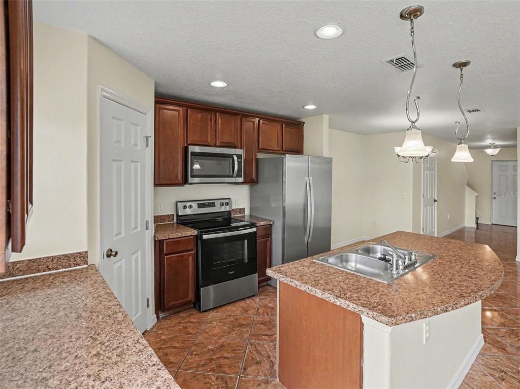 A kitchen features dark wood cabinets, stainless steel appliances, granite countertops, and a center island — 6105 TIMBER CREST DRIVE, ST CLOUD, FL