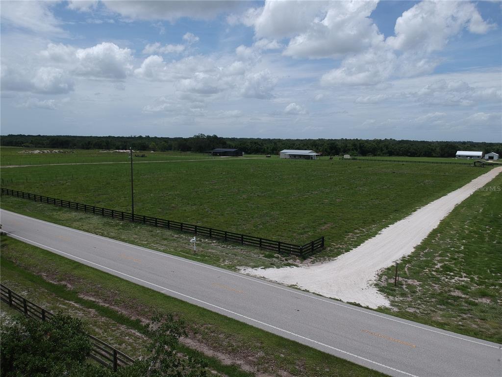 An aerial view shows a large, fenced grassy pasture bordering a paved road — 5081 SE CREEKSIDE LANE, ARCADIA, FL