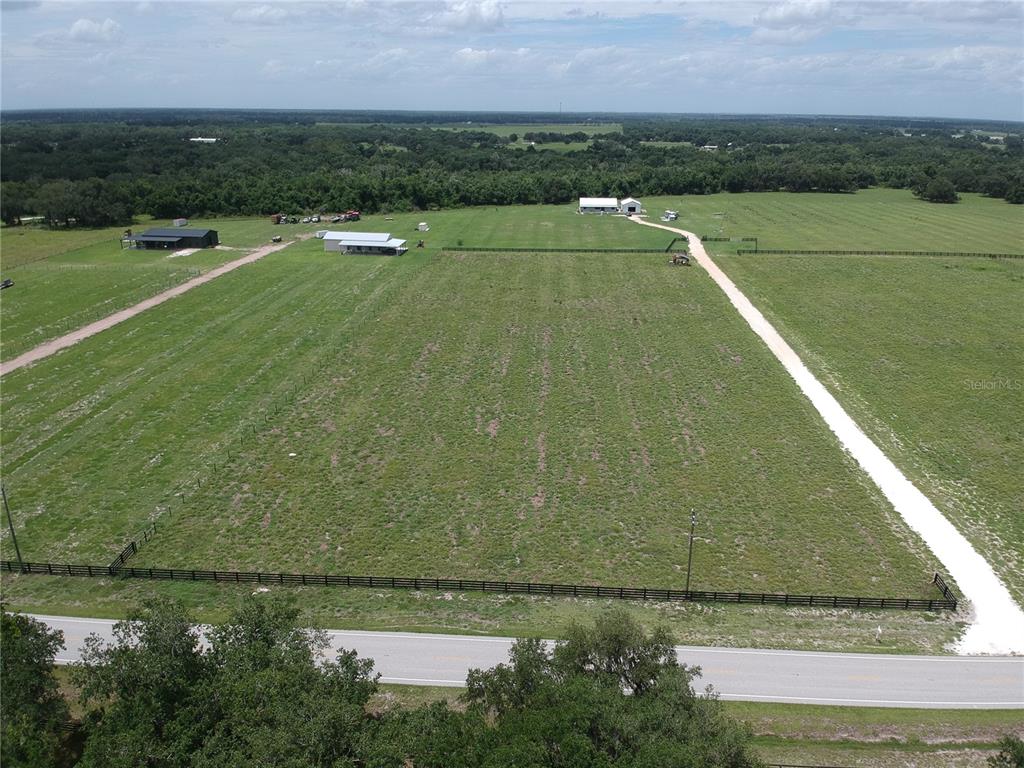 An aerial view shows a large, fenced grassy pasture with two buildings and a driveway — 5081 SE CREEKSIDE LANE, ARCADIA, FL