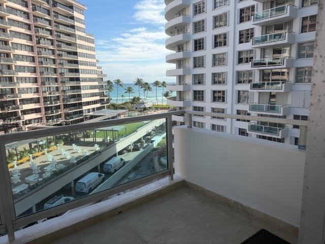 A balcony overlooks a parking area, two large apartment buildings, and the ocean in the distance — 5161 Collins Ave # 703, Miami Beach FL 33140, MIAMI BEACH, FL