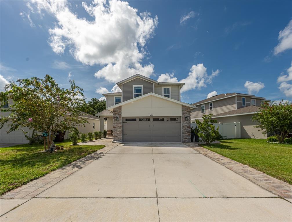 A two-story suburban house with a concrete driveway, stone accents, and a two-car garage — 4210 SOUTHERN VISTA LOOP, ST CLOUD, FL