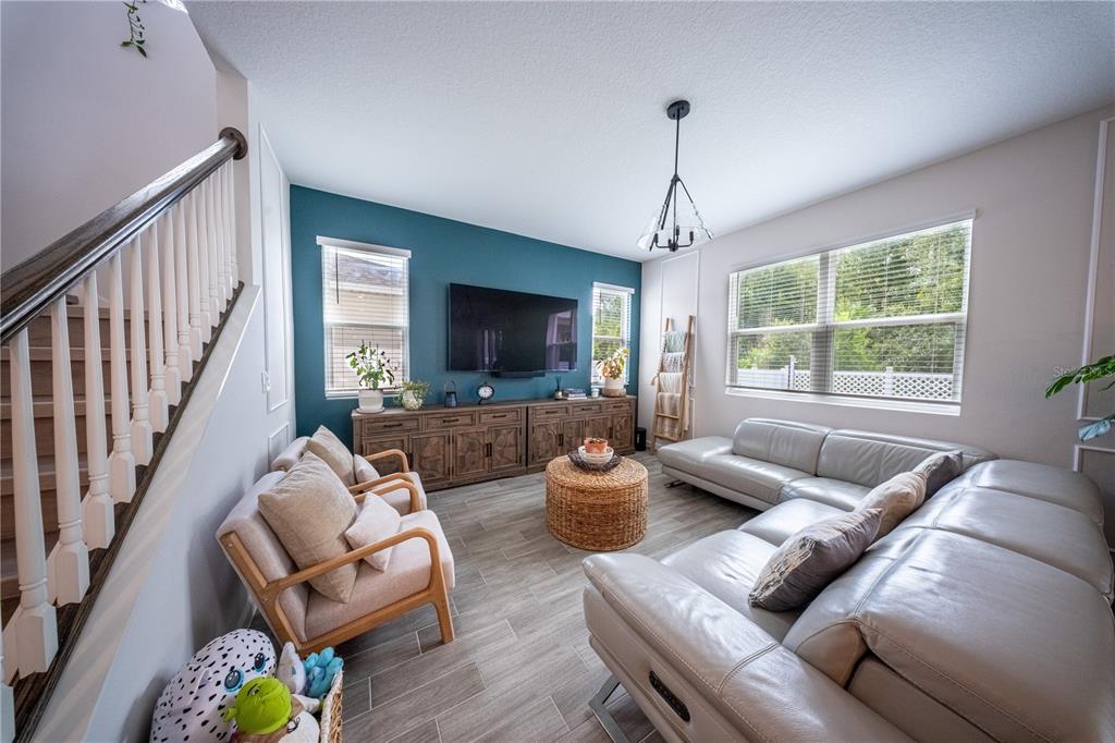 A living room features a teal accent wall, a large sectional sofa, and wood-look flooring — 4210 SOUTHERN VISTA LOOP, ST CLOUD, FL