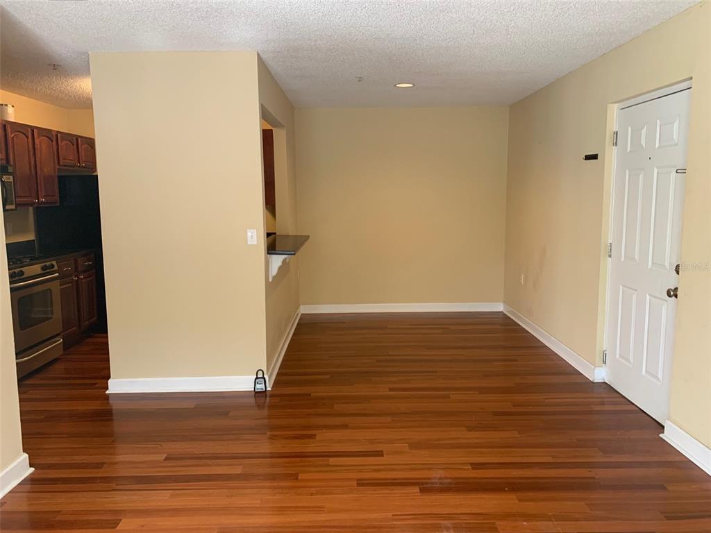 An empty dining area features hardwood floors, a kitchen pass-through window, and a white door — 2007 DIXIE BELLE DRIVE UNIT 2007D, ORLANDO, FL