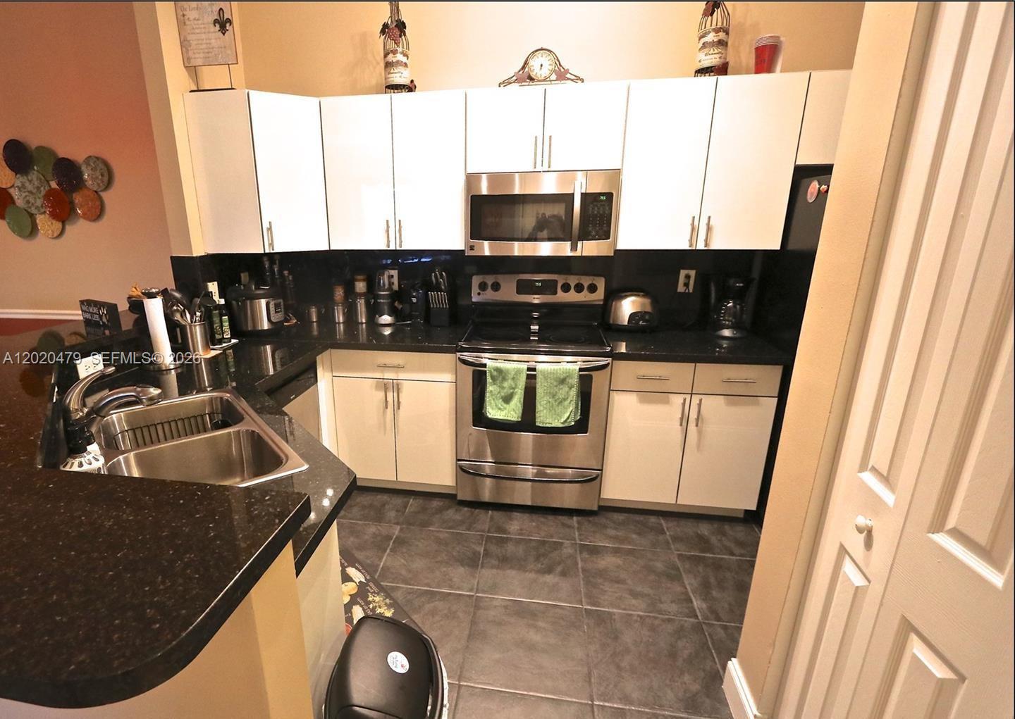 A kitchen features white cabinets, stainless steel appliances, and dark granite countertops — 4602 SW 160th Ave # 533, Miramar FL 33027, MIRAMAR, FL