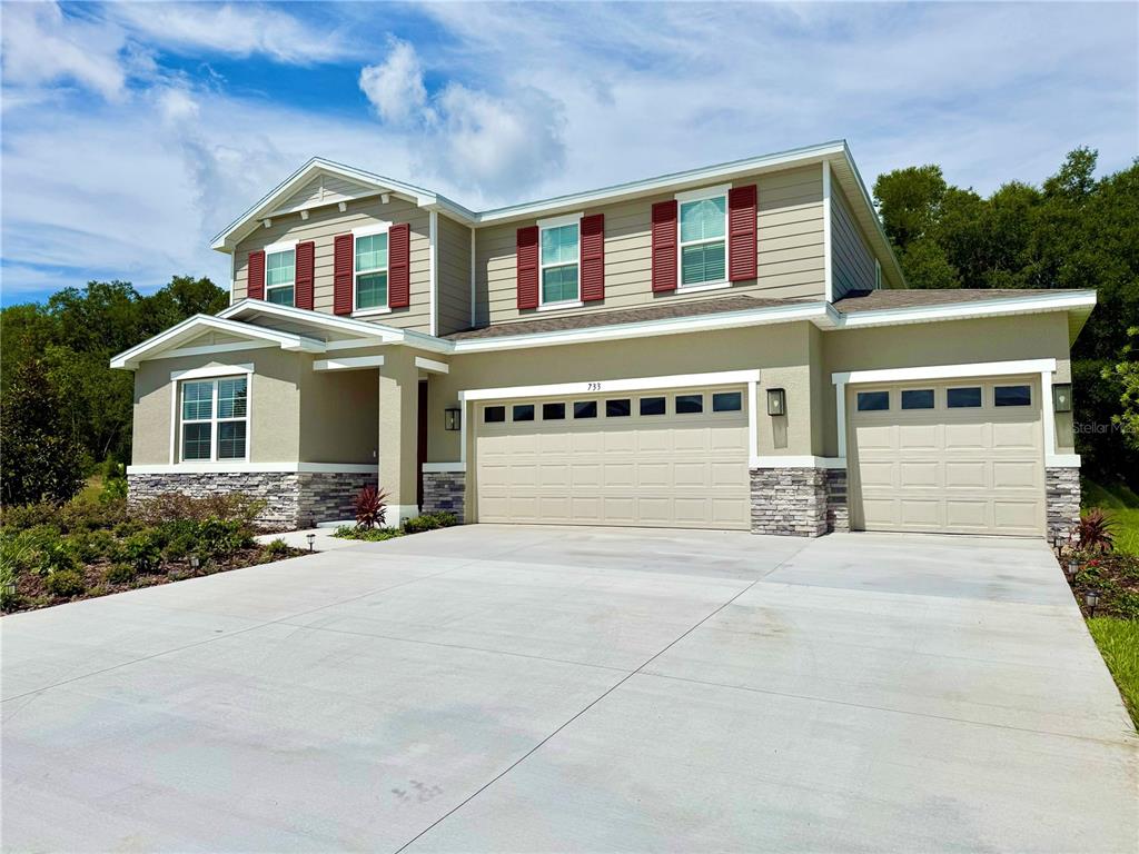 A two-story house with a three-car garage, stone accents, and red shutters — 733 WEKIVA RIDGE DRIVE, MOUNT DORA, FL